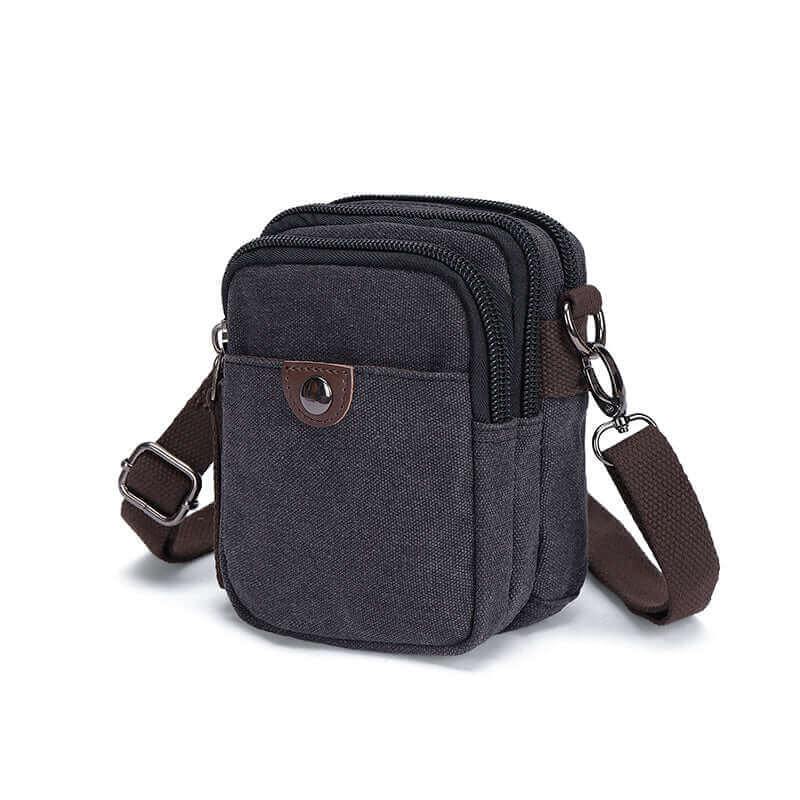 Black canvas small crossbody bag with brown strap.