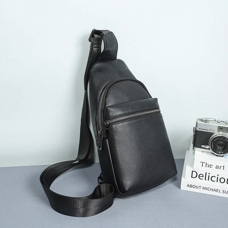 Black leather sling bag showcasing its adjustable strap for versatile wear.