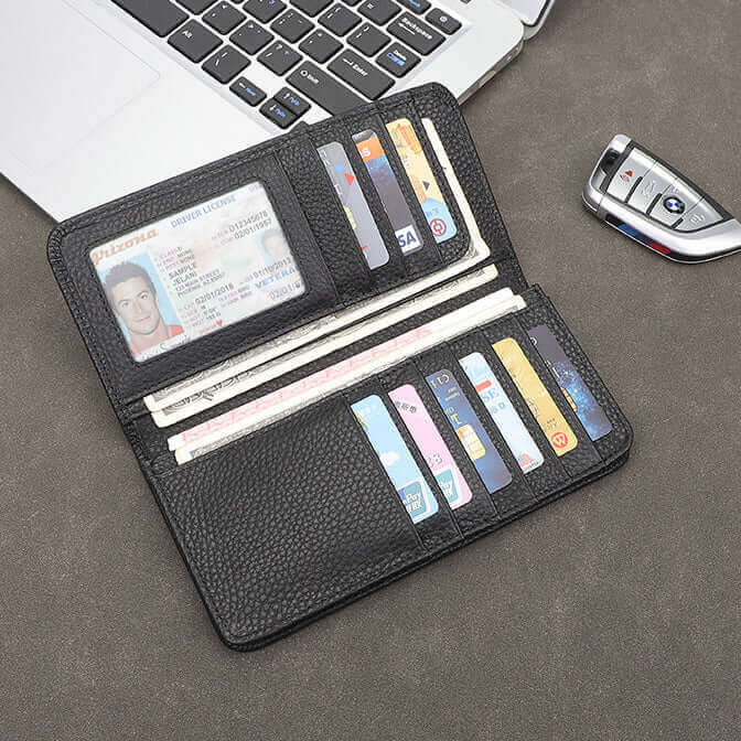 Black leather bifold wallet placed on desk with car key and laptop.