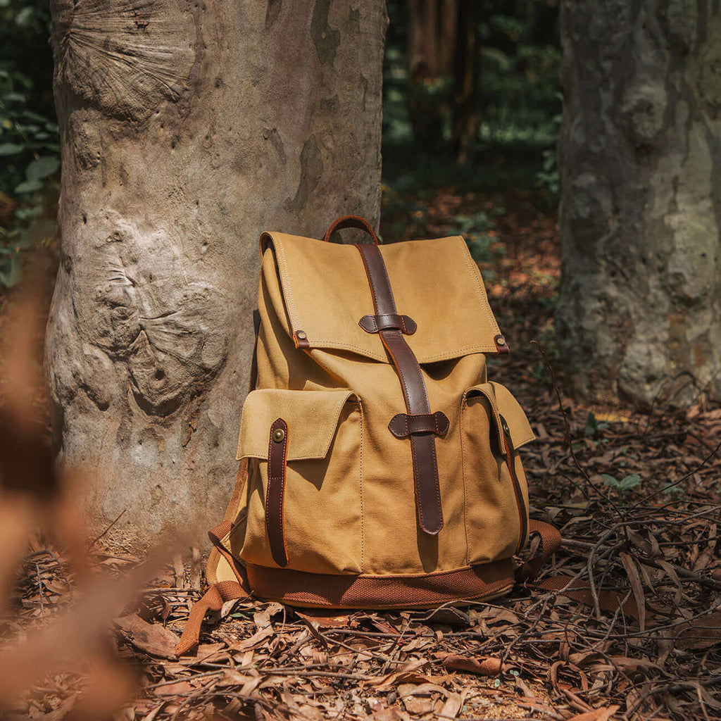 Brown canvas backpack designed to fit a 15.6-inch laptop, ideal for work or travel.