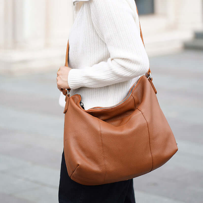 Brown leather shoulder bag styled with a casual outfit by a model.