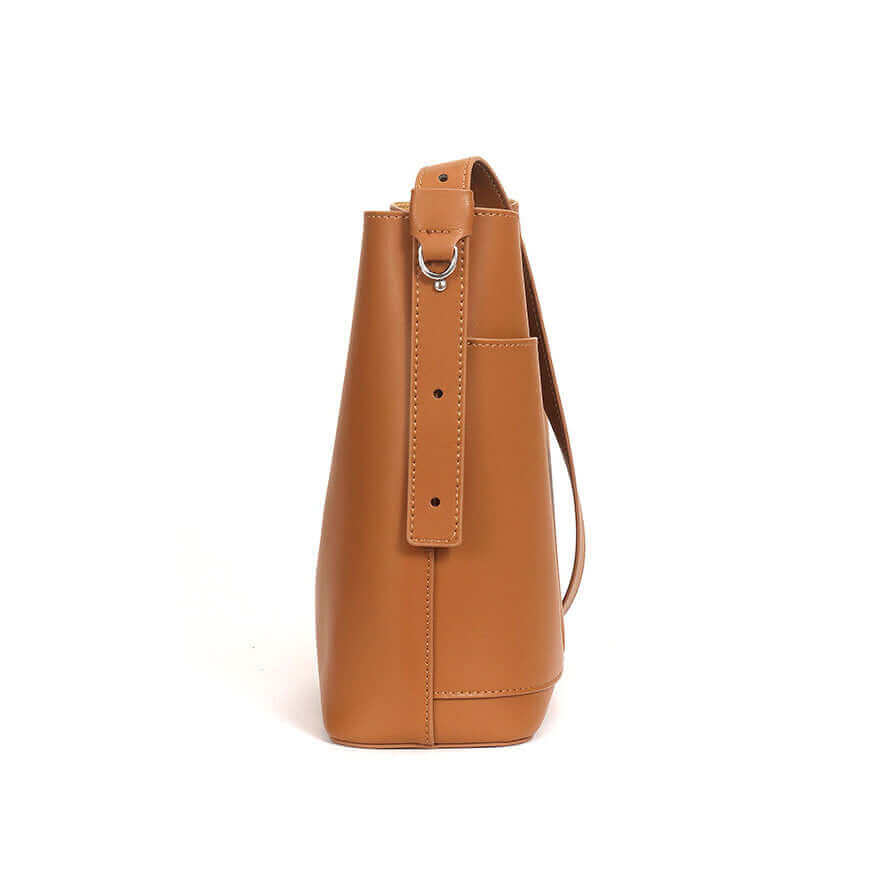 Side profile of minimalist leather bucket bag with shoulder strap.