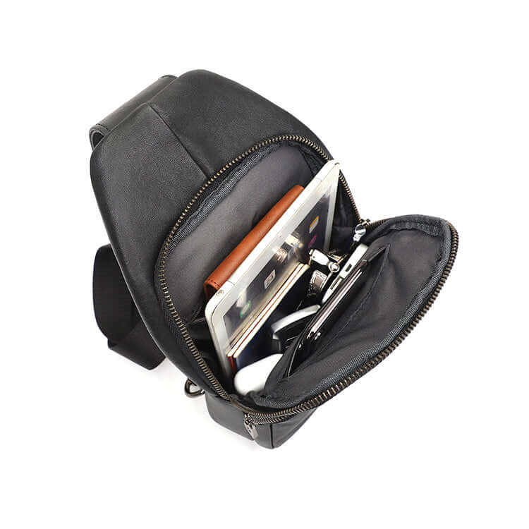 Open black leather chest bag showing zippered compartments.