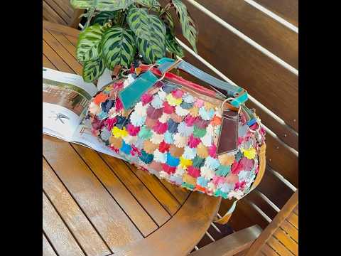 Colorful leather floral tote bag carried by hand.