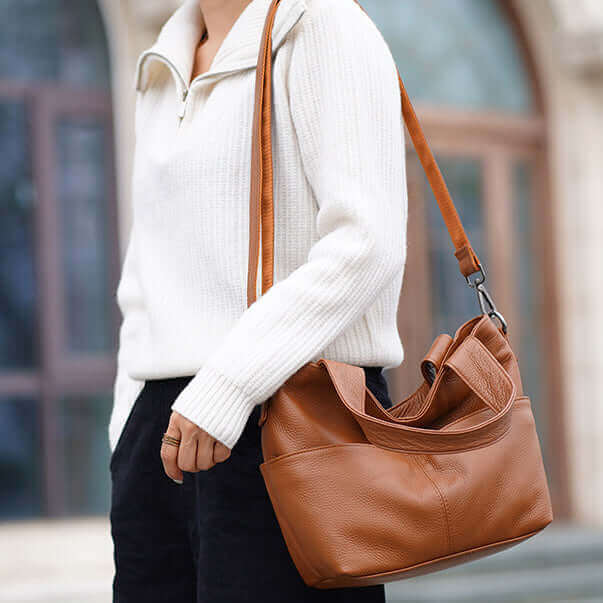 Woman carrying a leather tote handbag on her shoulder, highlighting its practical and stylish design.